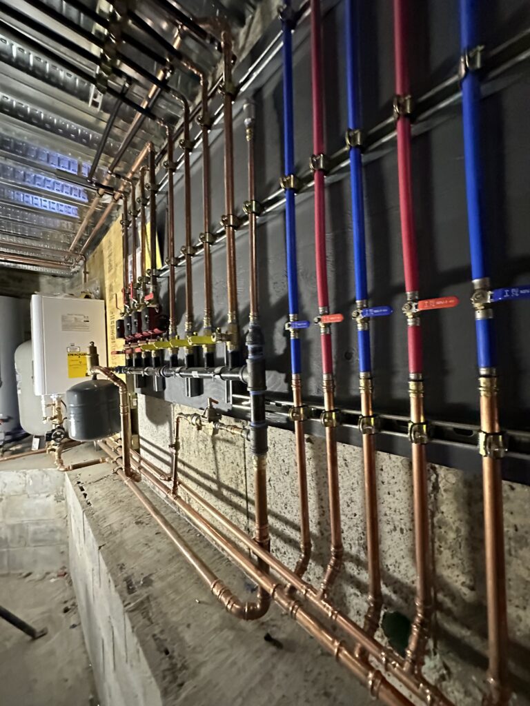 Copper and PEX repipe manifold with shutoff valves installed in a basement by Action Construction