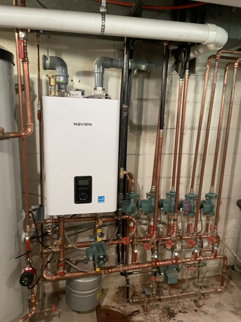Navien wall mounted boiler with copper near boiler piping and circulator pumps installed by Action Construction